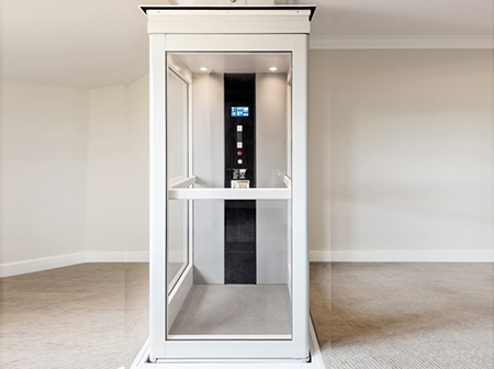 How Much Does A Home Elevator Cost. It's Interior view of a modern home elevator with glass walls and control panel.