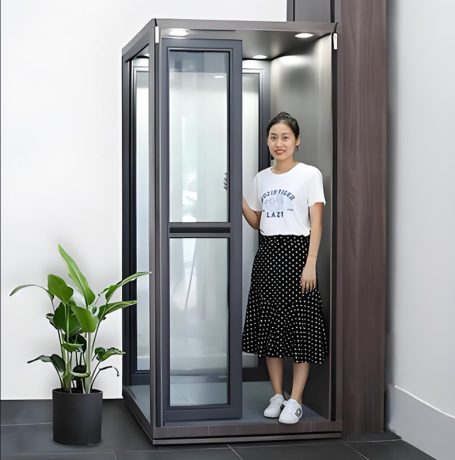 A woman standing inside a modern residential elevator with glass panels and a sleek design.