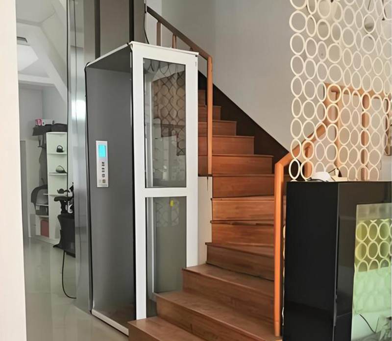 A small domestic home lift installed beside a staircase