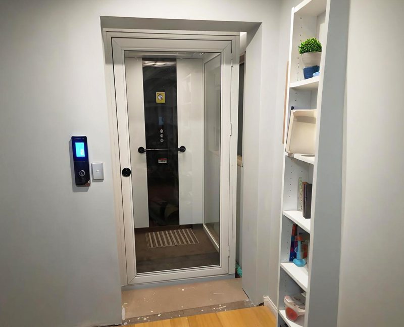 a white frame home elevator installed near the shelf.