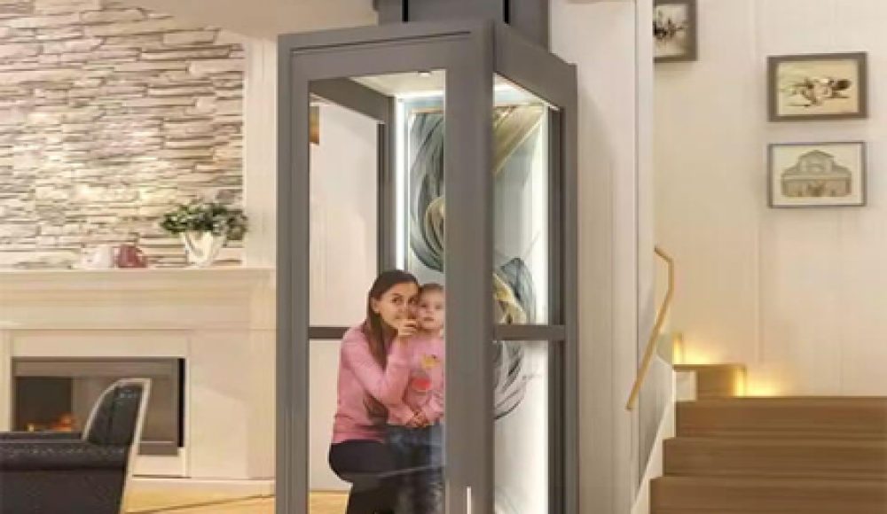A home lift featuring glass panels with a woman and child inside, installed in a modern interior near staircase.